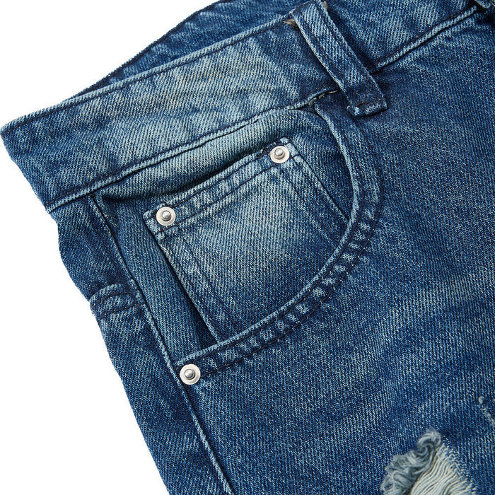 Close-up of front pocket on blue washed jeans with rivets and topstitching