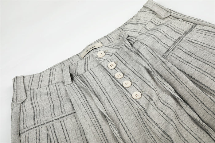 Close-up of the waistband and front button fly on gray striped pleated trousers