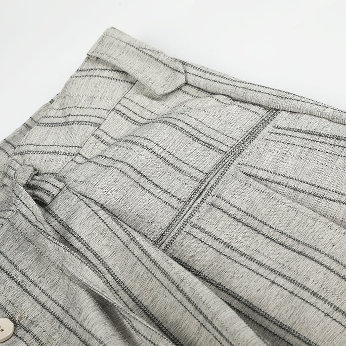 Close-up of the waistband and striped woven fabric on gray pleated trousers